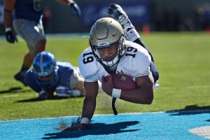 NCAA College Football Player crossing goal line with support of booster club