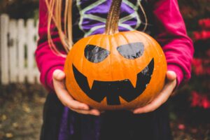 Kid holding a painted halloween pumpkin after attending a booster club fundraiser.