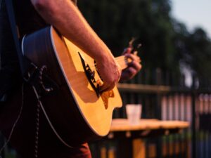 Man playing guitar for booster club virtual fundraiser.